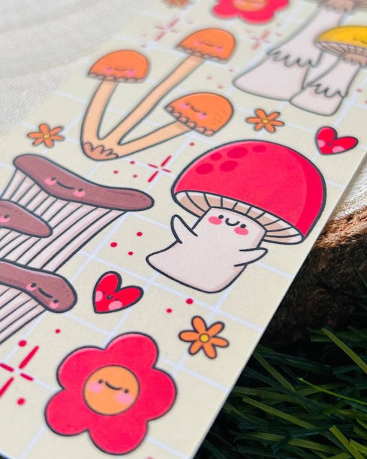 Close-up of the Fungi Cuties Bookmark by Kelly Lou, a velvet-laminated bookmark with smiling mushrooms and flowers. A whimsical, pastel-toned design available at Rebel Romance, a UK small biz that loves all things magical and alternative.
