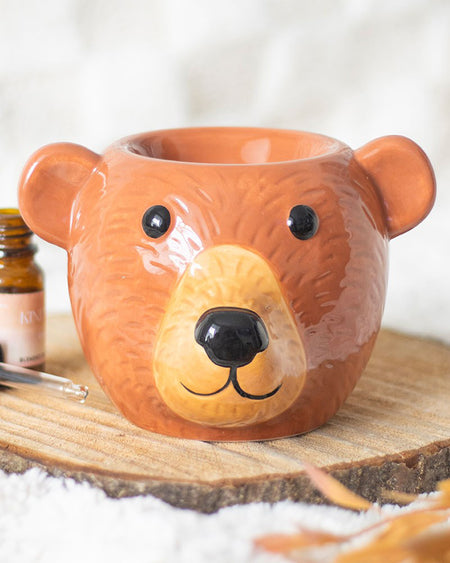 Styled shot of the Rebel Romance Bear Oil Burner placed on a rustic wood slice with cosy textures and autumnal tones. This adorable ceramic bear burner is ideal for adding warmth and scent to your home while fitting right in with your seasonal décor.