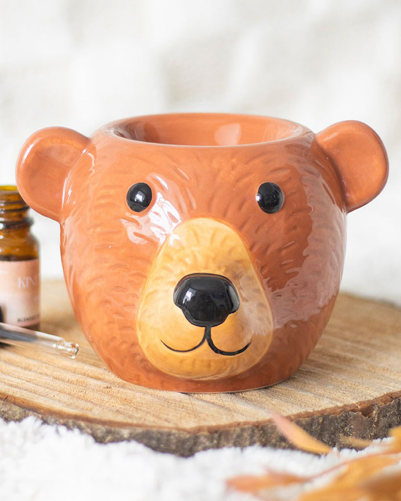 Styled shot of the Rebel Romance Bear Oil Burner placed on a rustic wood slice with cosy textures and autumnal tones. This adorable ceramic bear burner is ideal for adding warmth and scent to your home while fitting right in with your seasonal décor.