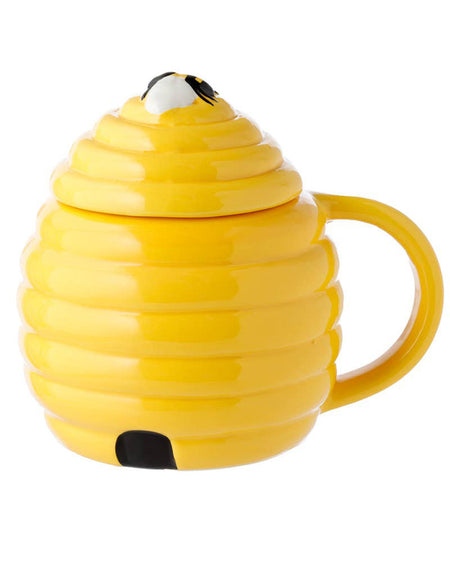 A side view of the yellow beehive-shaped ceramic mug with the lid on, highlighting the 3D bee on top and a small painted bee entrance. A playful and practical cottagecore mug from Rebel Romance.