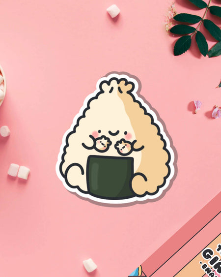 Kawaii dumpling onigiri vinyl sticker designed by Toastedink, featuring a cheerful character with blushing cheeks and mini dumplings. Displayed on a pink backdrop, perfect for Rebel Romance’s collection of whimsical stationery and gifts.