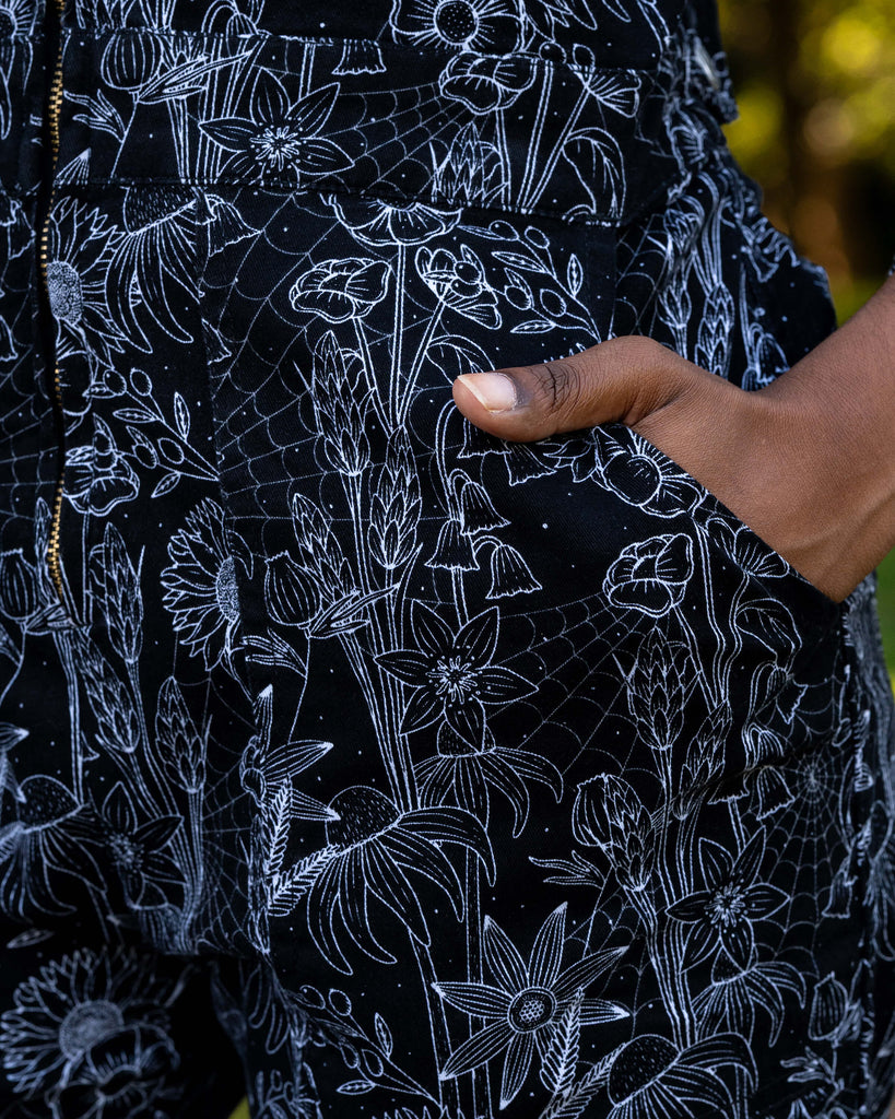Detail of the Rebel Romance Black Floral Cobweb Boilersuit showing the floral and cobweb print with zip front fastening. Ethically made alternative fashion in black and white stretch twill.