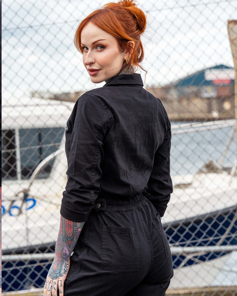 Erin turns slightly to show the back of the boiler suit, highlighting the stretchy back panel and pocket details.