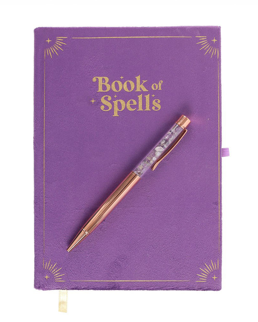 Flat lay of the Book of Spells journal with an amethyst crystal pen. The purple velvet cover features gold-foiled sunburst corner details and the title Book of Spells in a mystical, serif font.
