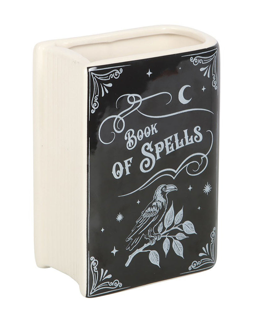 Front-facing view of the Rebel Romance Book of Spells book-shaped ceramic vase. The black and cream vase is styled to look like a magical spell book with a raven and moonlit design, ideal for gothic home lovers.
