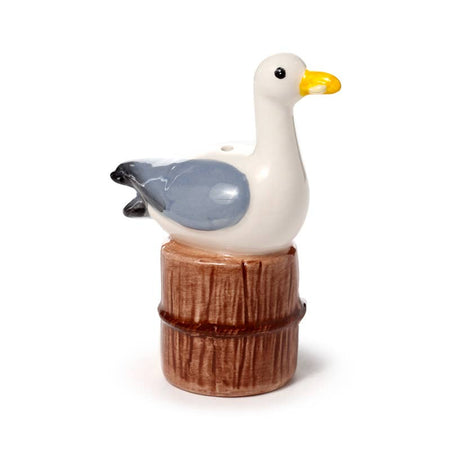 A ceramic salt or pepper shaker shaped like a seagull sitting on a wooden post. Hand-painted with coastal-inspired details in grey, white, yellow, and brown. Part of the nautical-themed Seagull Buoy Salt & Pepper Set from Rebel Romance.