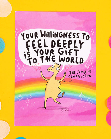 A colourful A6 postcard featuring an illustration by Katie Abey of a smiling camel on a pink and rainbow background. The text reads “Your willingness to feel deeply is your gift to the world” with the character labelled “The Camel of Compassion.” Whimsical, emotional, and uplifting design.