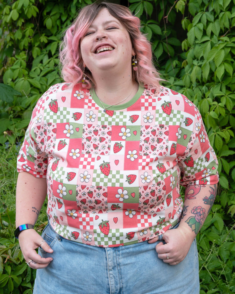Front view of Sam modelling the Strawberry Picnic tee with a relaxed fit and tucked into high-waisted light blue jeans.
