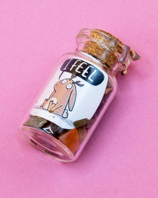 A small glass spell bottle sealed with wax and filled with herbs and crystals, featuring a label with a cute illustrated jackalope and the words "I Feel". Handmade by Happiness Enchanters and available at Rebel Romance, a UK brand celebrating alternative aesthetics and magical gifts.
