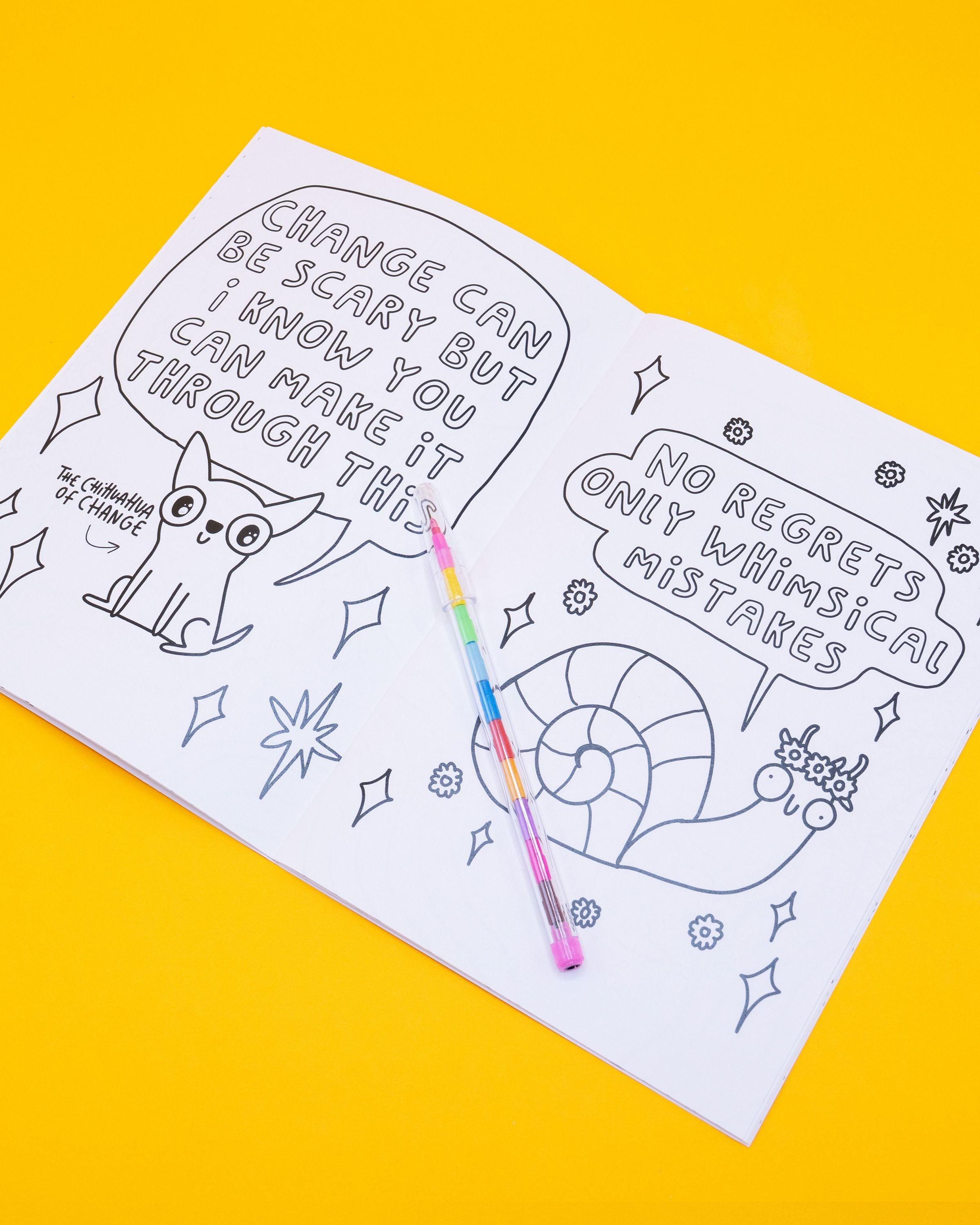 Open page of the Stay Whimsical Magical Colouring Book by Katie Abey, featuring two illustrations. Left page has “The Chihuahua of Change” with text: “Change can be scary but I know you can make it through this.” Right page shows a smiling snail with text: “No regrets only whimsical mistakes.” A rainbow pen rests across the book.