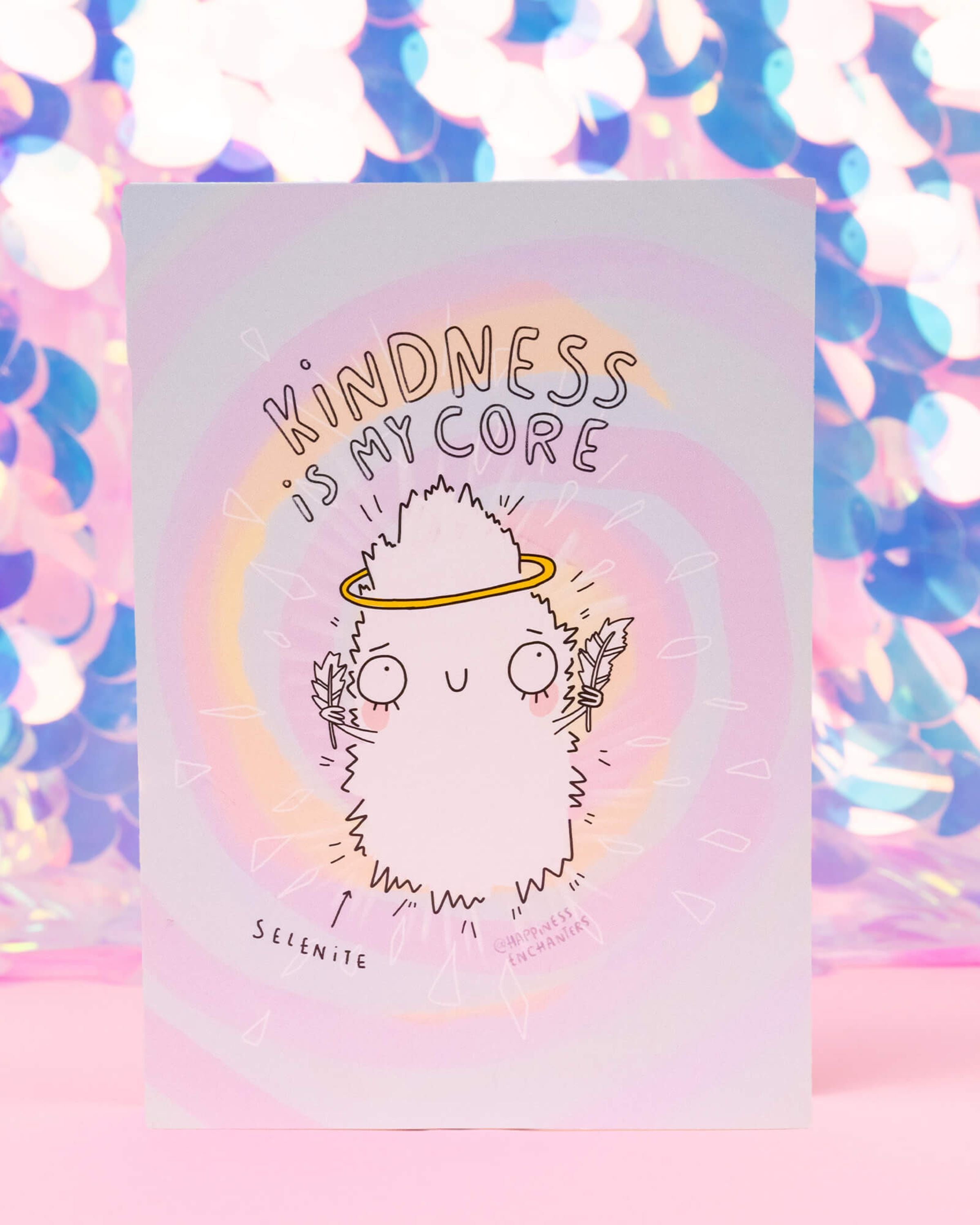 Cute pastel postcard from Rebel Romance featuring a white Selenite crystal character with a yellow halo and feathers in its hands. Surrounded by a dreamy swirl of rainbow colours, the text above reads “Kindness is my core”. Illustrated by Katie Abey for Happiness Enchanters, this A6 postcard spreads a gentle message of love, healing, and self-care, perfect for gifting or framing.