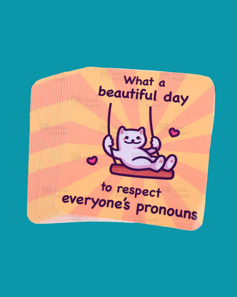 Vinyl sticker featuring a cute white cartoon cat on a swing with hearts and the text “What a beautiful day to respect everyone’s pronouns” in bold black font. The background has orange and yellow sunburst rays. A supportive LGBTQ+ pride design for trans, non-binary, and gender-fluid folks. Designed by Mona Mauve and sold by Rebel Romance, a small UK business celebrating queer joy and inclusivity.