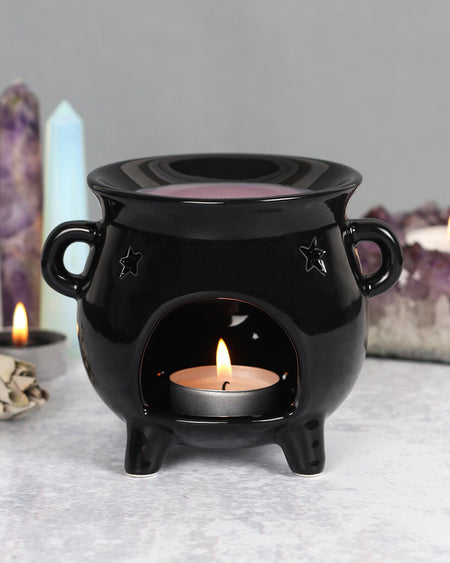Styled shot of the Cauldron Oil Burner with a lit tealight inside, surrounded by crystals and candles. Perfect for adding magical vibes to any space.