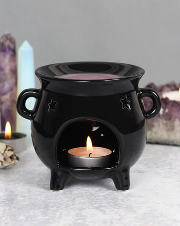 Styled shot of the Cauldron Oil Burner with a lit tealight inside, surrounded by crystals and candles. Perfect for adding magical vibes to any space.