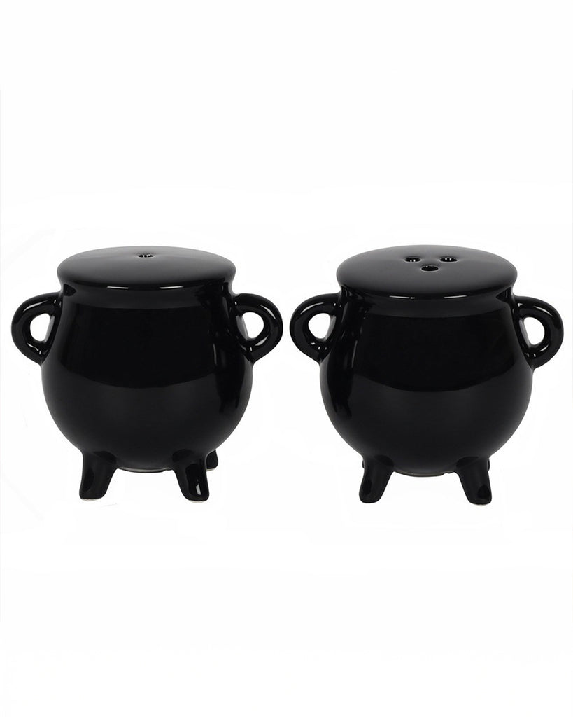 Cauldron Salt & Pepper Shaker Set displayed against a white background. Each glossy black ceramic shaker stands on three legs with two side handles. One has a single-hole top, and the other has three holes. A perfect gift for alternative home decor lovers. Available from Rebel Romance, a UK small business.