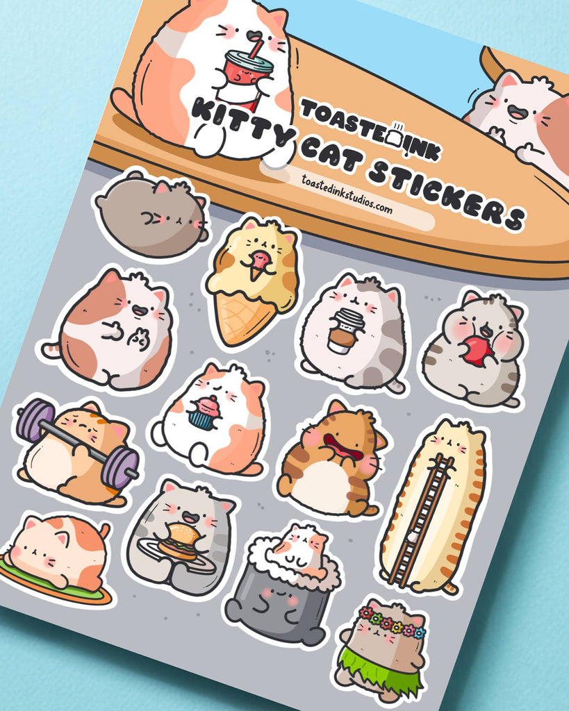 Angled flatlay of Toastedink's Kitty Cat Sticker Sheet from Rebel Romance. Packed with 15 funny and cute cat stickers including a burger-eating cat, cupcake cat and a tall stretchy cat. Perfect for gifting or journaling.