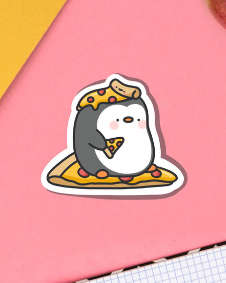 Penguin eating pizza vinyl sticker designed by Toastedink. Shown on a pink backdrop, the penguin sits on a pizza slice and wears one like a hat. A fun and waterproof vinyl sticker available at Rebel Romance, ideal for gifts and stationery.