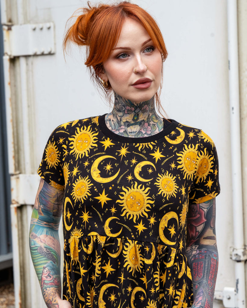 Close-up of Erin modelling the Rebel Romance Celestial Midi Dress in stretch cotton. The celestial print shows golden suns, crescent moons, and stars on a black background, creating a striking witchy and alternative look.