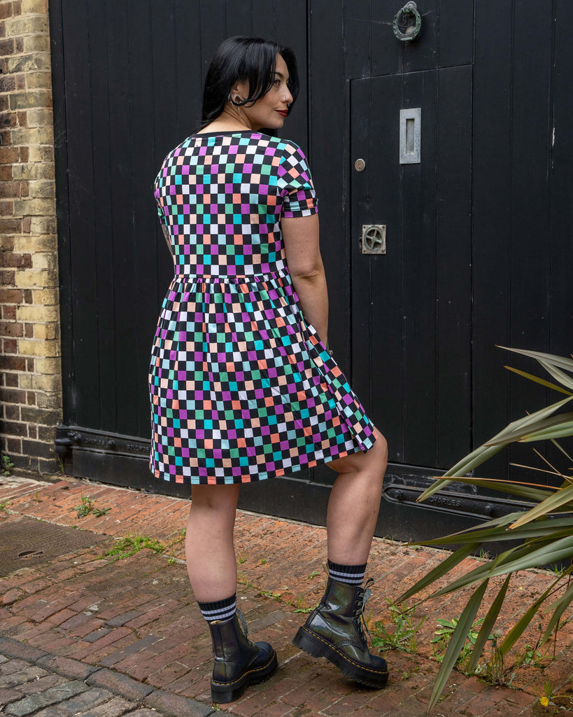Back view of Carmen wearing the Rebel Romance Checkerboard Stretch Smock Dress. The multicoloured check print and casual smock silhouette make it a great wardrobe staple for alternative, size-inclusive fashion.