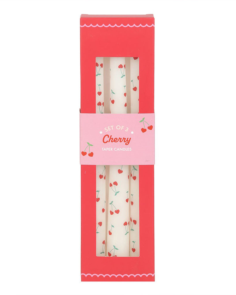 Close-up of a hand holding the three Heart Cherry Taper Candles against a playful pink background with scattered cherry illustrations. This shot emphasises the candles' retro aesthetic, perfect for Valentine's Day or adding a pop of colour to your decor.