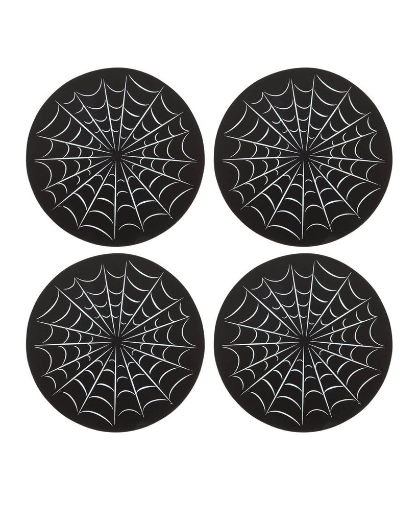  Close-up of four round black coasters with white spiderweb designs, laid flat in a group.
