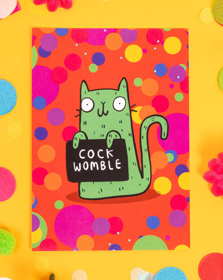 A bold A6 postcard featuring a cartoon green cat holding a sign that says “Cock Womble” against a bright orange background with multicoloured confetti dots. Designed by Katie Abey, this cheeky and colourful card is ideal for millennials who love sweary humour, quirky stationery, and fun alternative gifts.