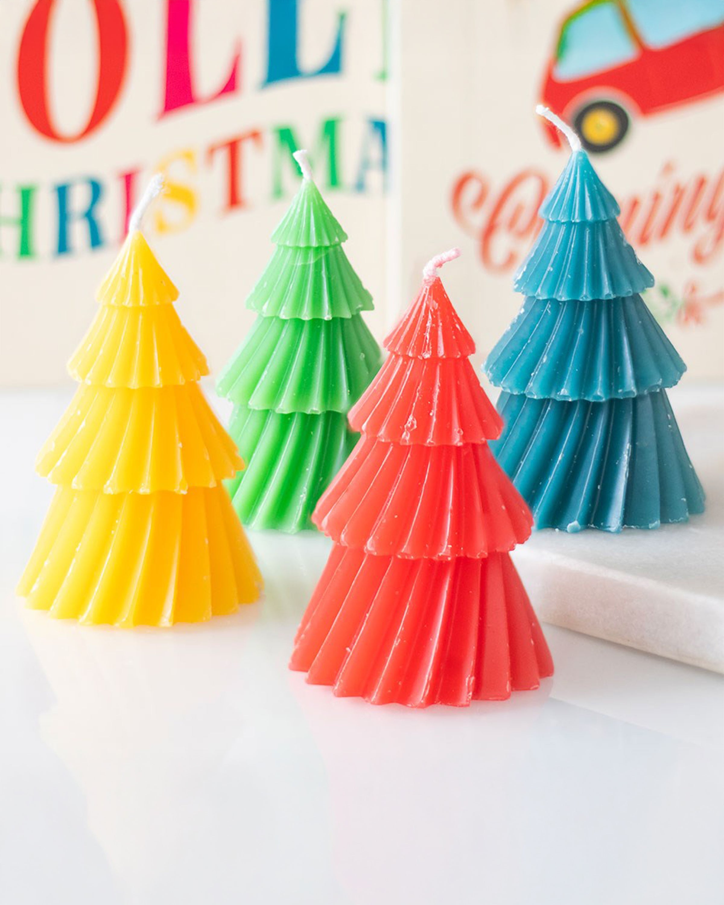 Close-up of Rebel Romance colourful Christmas tree candles in red, blue, green and yellow. These quirky unscented candles brighten up festive styling, perfect for creating a bold centrepiece or gifting to someone who loves extraordinary, artistic homeware with a millennial-friendly vibe.