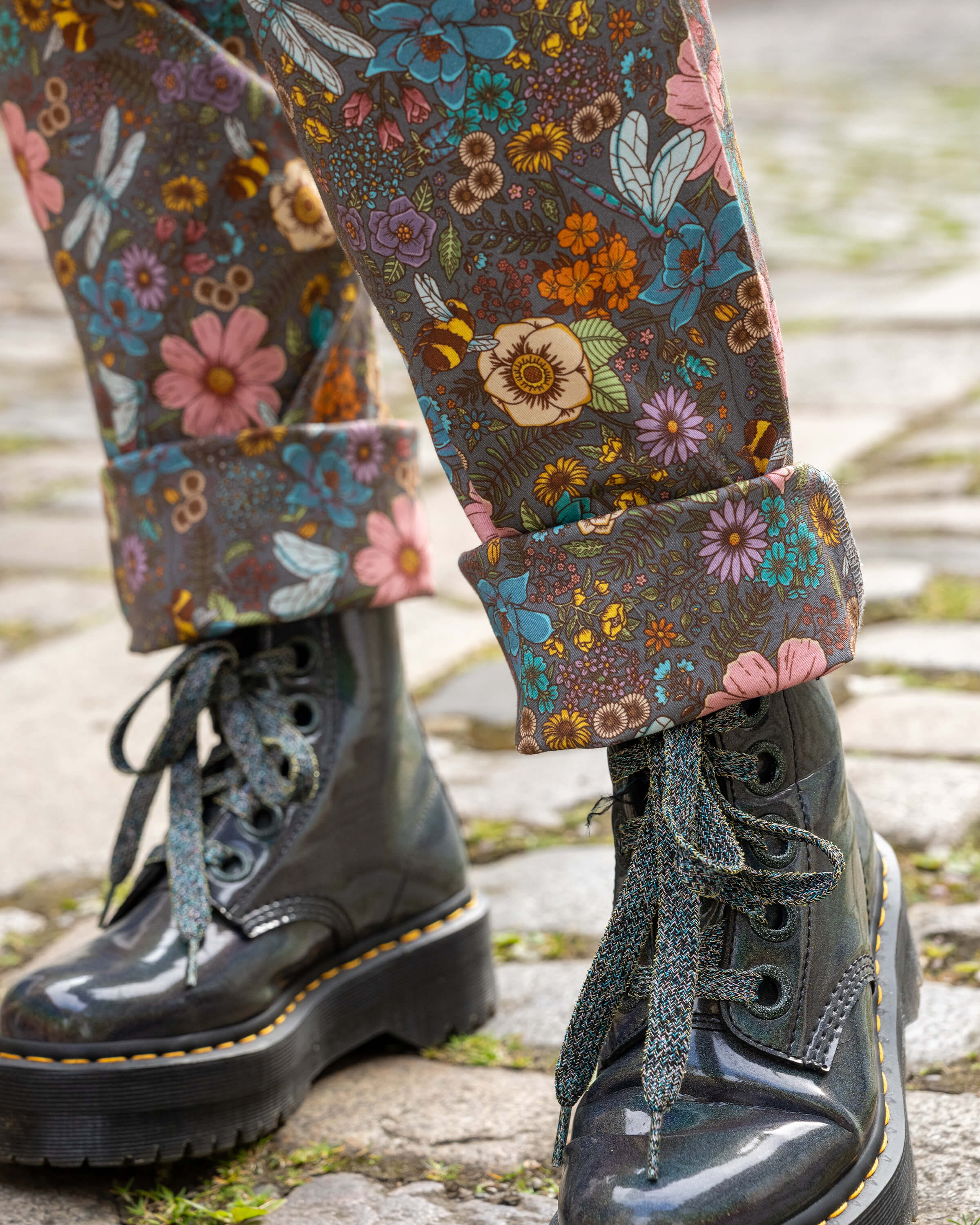 Close-up of the matching turn ups on the Rebel Romance CottageCore Dungarees, highlighting detailed illustrations of dragonflies, bees, blue and orange flowers against a muted base.