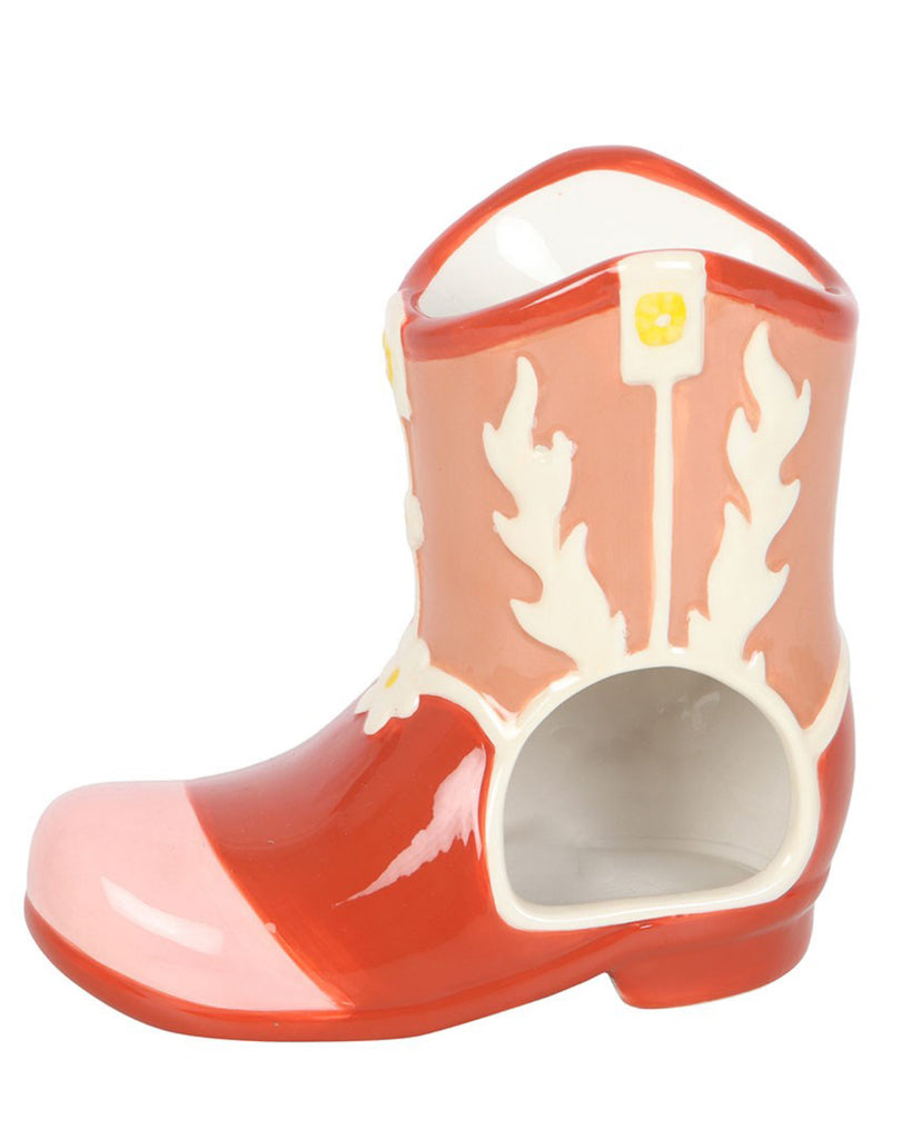 Close-up of a ceramic pink cowboy boot-shaped oil burner with floral details and an opening for a tealight candle