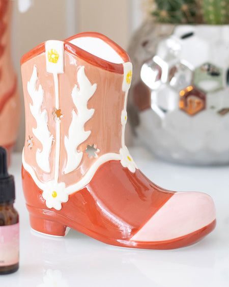 Side view of the pink and orange ceramic cowboy boot oil burner showing a cut-out section for placing a tealight candle inside.