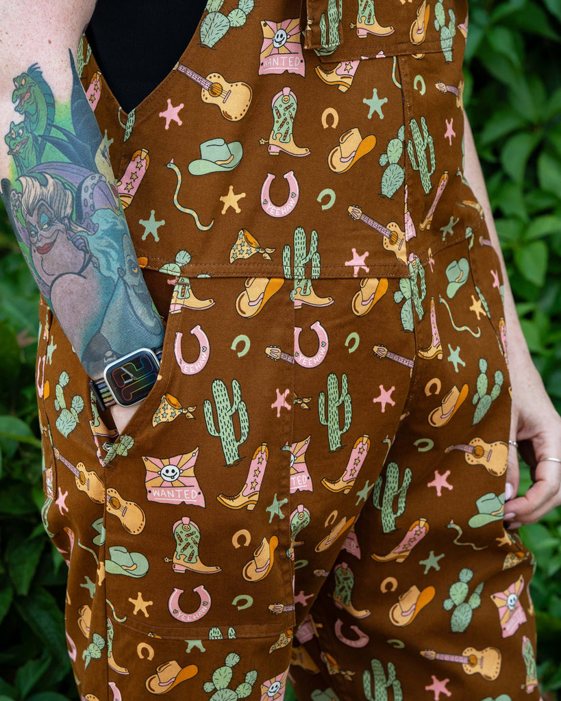 Close-up of the side pocket on Rebel Romance x Yasmin Cousins Cowboy Dungarees, printed with cowboy boots, guitars, cacti and stars.