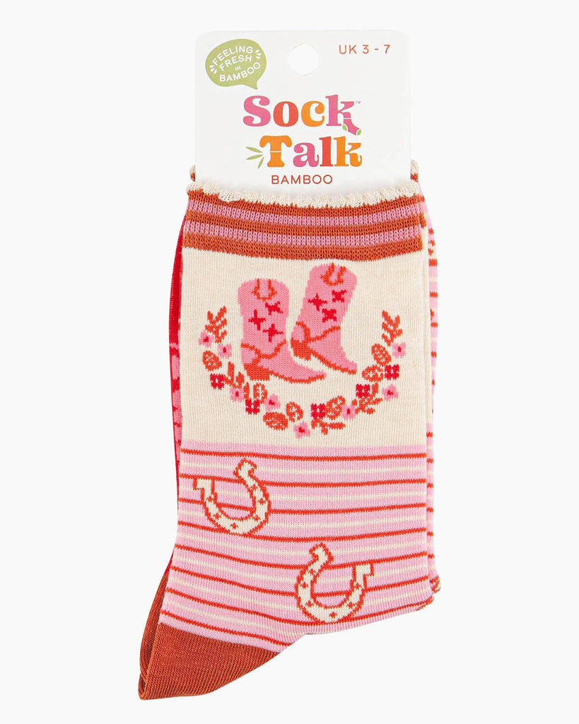 (Packaged Socks): A pair of folded Wild West-themed socks inside their Sock Talk bamboo packaging, featuring a vintage-style cowboy boot and floral pattern with red pinstripes and a soft scalloped cuff.
