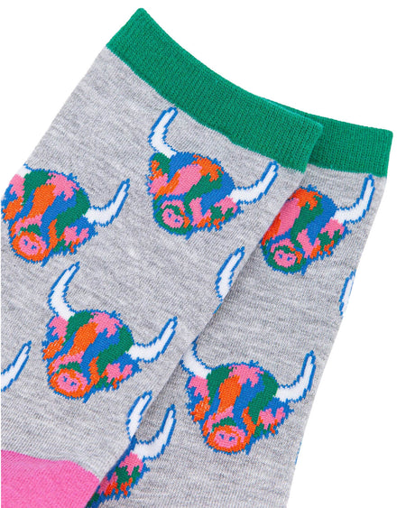 (Close-Up of Socks): A detailed view of the bamboo Highland cow socks, highlighting the rainbow-coloured fur, white horns, and fun pixelated design. The green ribbed cuff adds a contrast detail.
