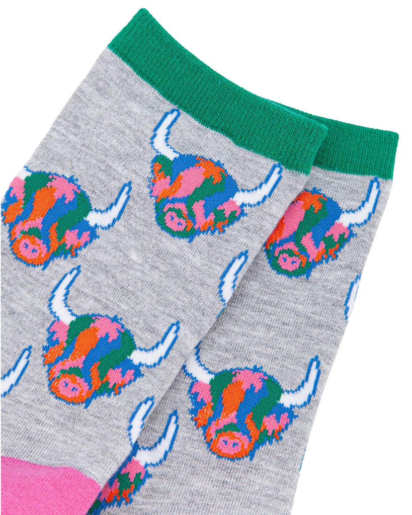 (Close-Up of Socks): A detailed view of the bamboo Highland cow socks, highlighting the rainbow-coloured fur, white horns, and fun pixelated design. The green ribbed cuff adds a contrast detail.
