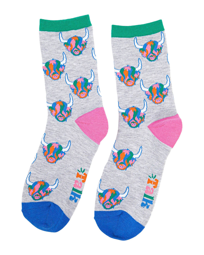 (Flat Lay of Socks): A pair of bamboo Highland cow socks laid flat, showcasing the vibrant rainbow cow design, green cuff, pink heel, and blue toe. The Sock Talk logo is woven near the foot area.
