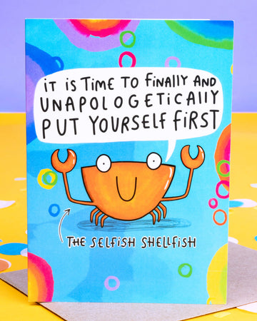 Bright and colourful A6 greeting card by Rebel Romance featuring The Selfish Shellfish by Katie Abey. The card shows a smiling orange crab on a blue background with rainbow bubbles, holding up claws beneath the message: “It is time to finally and unapologetically put yourself first.” A fun, motivational card designed to encourage self-care and self-love. Printed in the UK.