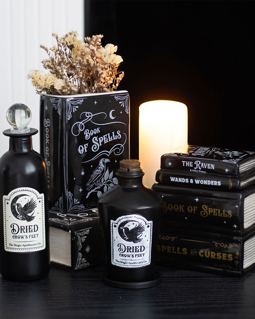 A gothic-style resin incense cone holder shaped like a black potion bottle labelled “Dried Crow’s Feet” from Rebel Romance, styled among spell books, dried flowers and candlelight for a spooky home decor vibe.