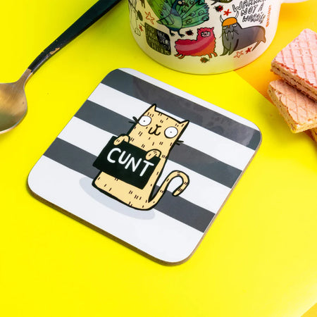 A very naughty swearing yellow cat holding a sign that says 'c*nt' on a black and what striped background. Designed by Katie Abey 