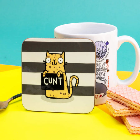 A very naughty swearing yellow cat holding a sign that says 'c*nt' on a black and what striped background. Designed by Katie Abey 