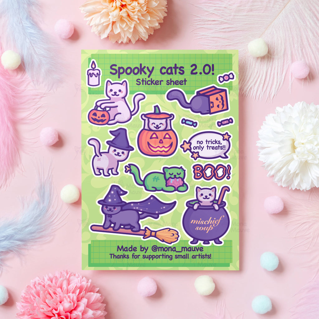 Flat lay of the Spooky Cats 2.0 Halloween Sticker Sheet by Mona Mauve, featuring cute illustrated cats in witch hats, pumpkins, broomsticks, potion cauldrons, and spooky phrases like “BOO!” and “no tricks, only treats!!” Set on a pastel pink background with flowers and pompoms. A fun Halloween gift for cat lovers and sticker collectors.