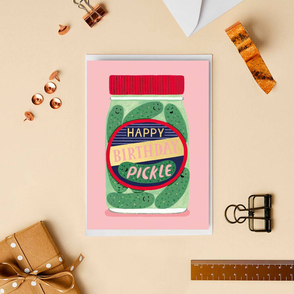 A close-up of the “Happy Birthday Pickle” card, styled with golden push pins and a ribbon. The design features a pickle jar with a bold and cheerful label, combining humour with a luxurious gold foil finish.