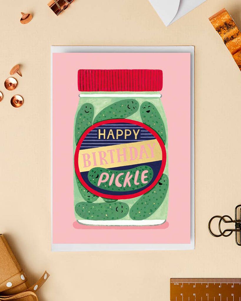 A close-up of the “Happy Birthday Pickle” card, styled with golden push pins and a ribbon. The design features a pickle jar with a bold and cheerful label, combining humour with a luxurious gold foil finish.