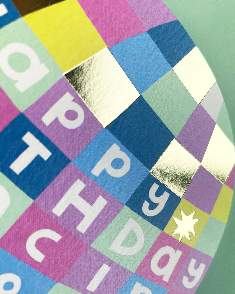 Close-up of Happy Birthday Dancing Queen card showing vibrant disco ball pattern with metallic gold foil accents and retro lettering.
