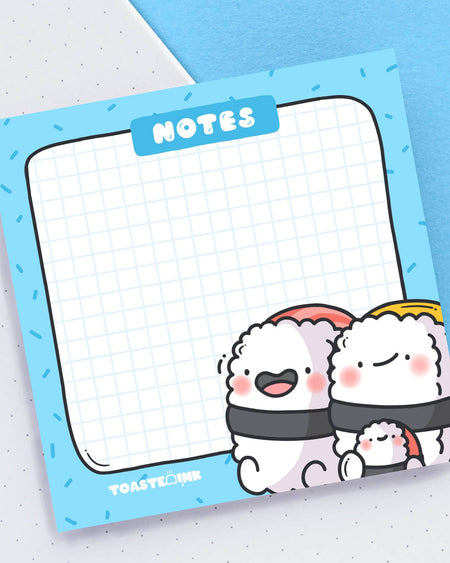 Close-up of Toastedink’s sushi-themed sticky notes featuring kawaii sushi characters in the corner, with a blue grid layout and “NOTES” at the top. Available from Rebel Romance in the UK.