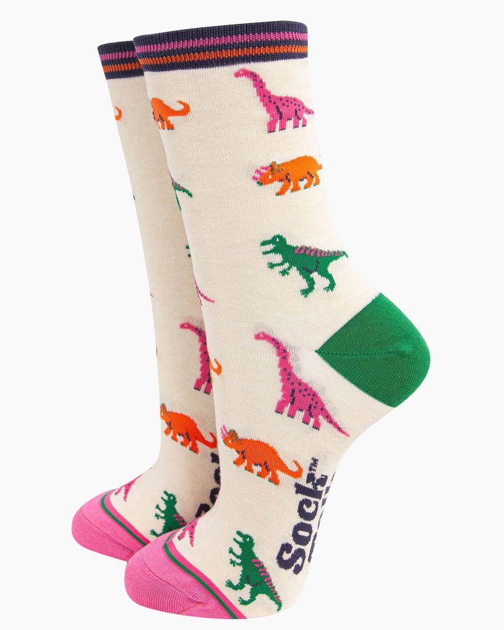A pair of cream bamboo socks with a playful dinosaur print featuring green T-Rex, pink brachiosaurus, and orange triceratops, finished with contrasting pink toes, green heels, and a striped cuff.