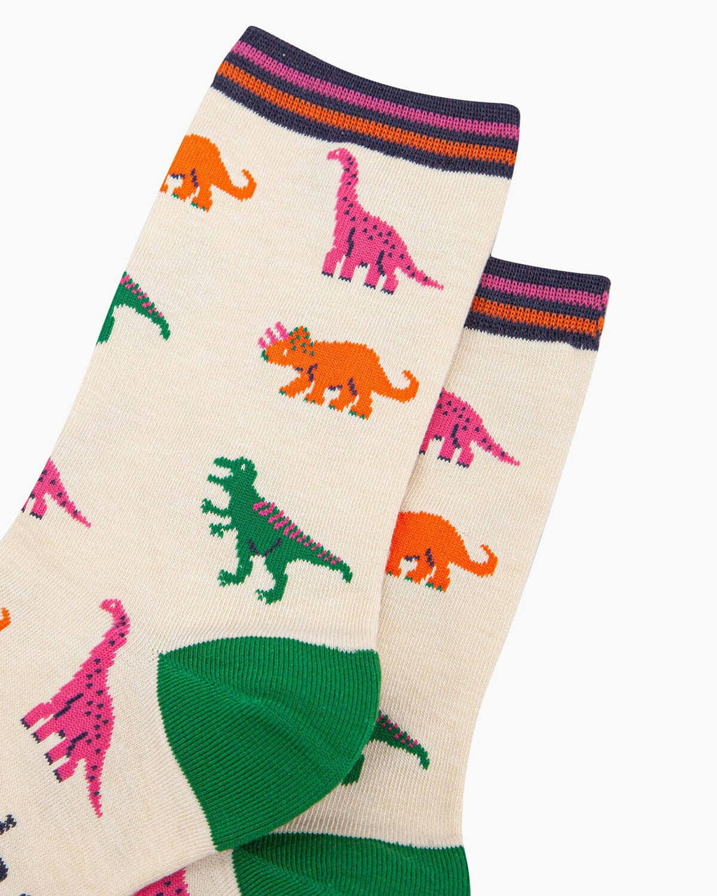 close up of A pair of cream bamboo socks with a playful dinosaur print featuring green T-Rex, pink brachiosaurus, and orange triceratops, finished with contrasting pink toes, green heels, and a striped cuff.