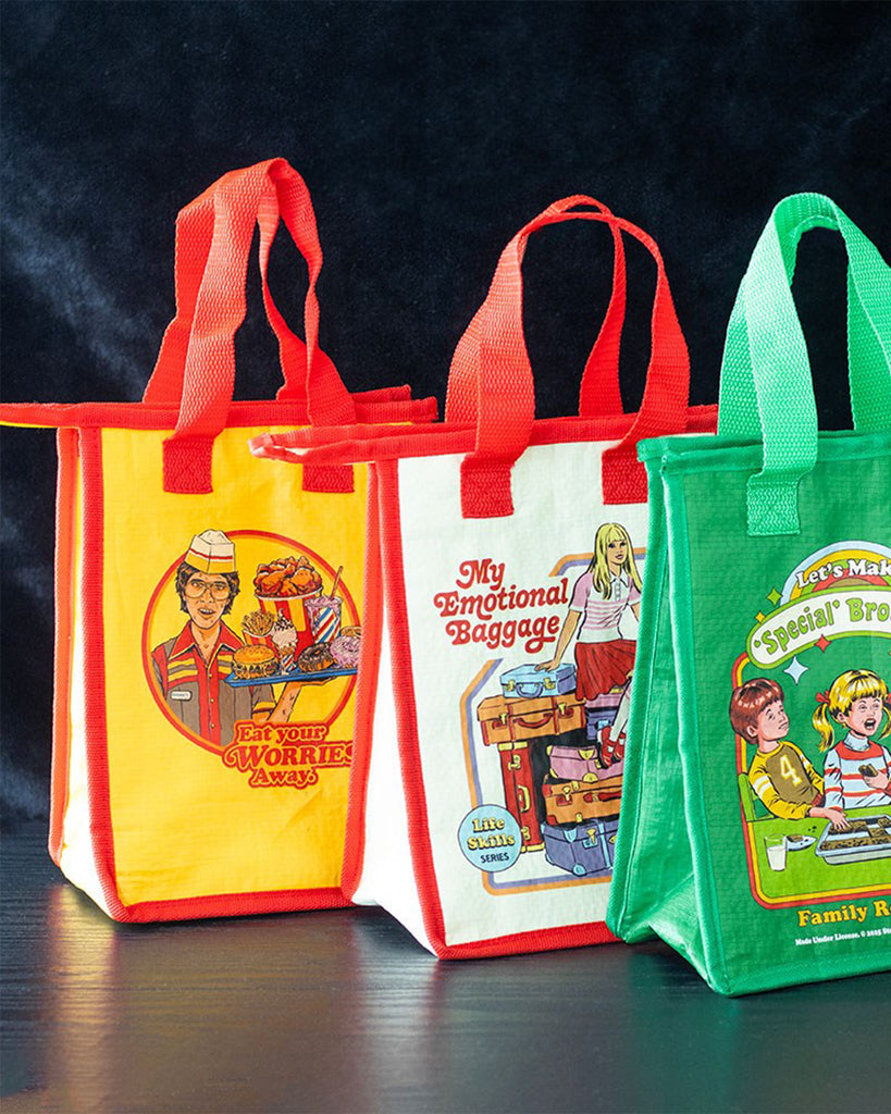Three retro Steven Rhodes lunch bags sold by Rebel Romance, a UK alternative fashion and lifestyle brand. Designs include "Eat Your Worries Away" with a fast-food worker, "My Emotional Baggage" with a girl and suitcases, and "Let’s Make Special Brownies." Colourful, quirky insulated lunch bags with bold vintage artwork.