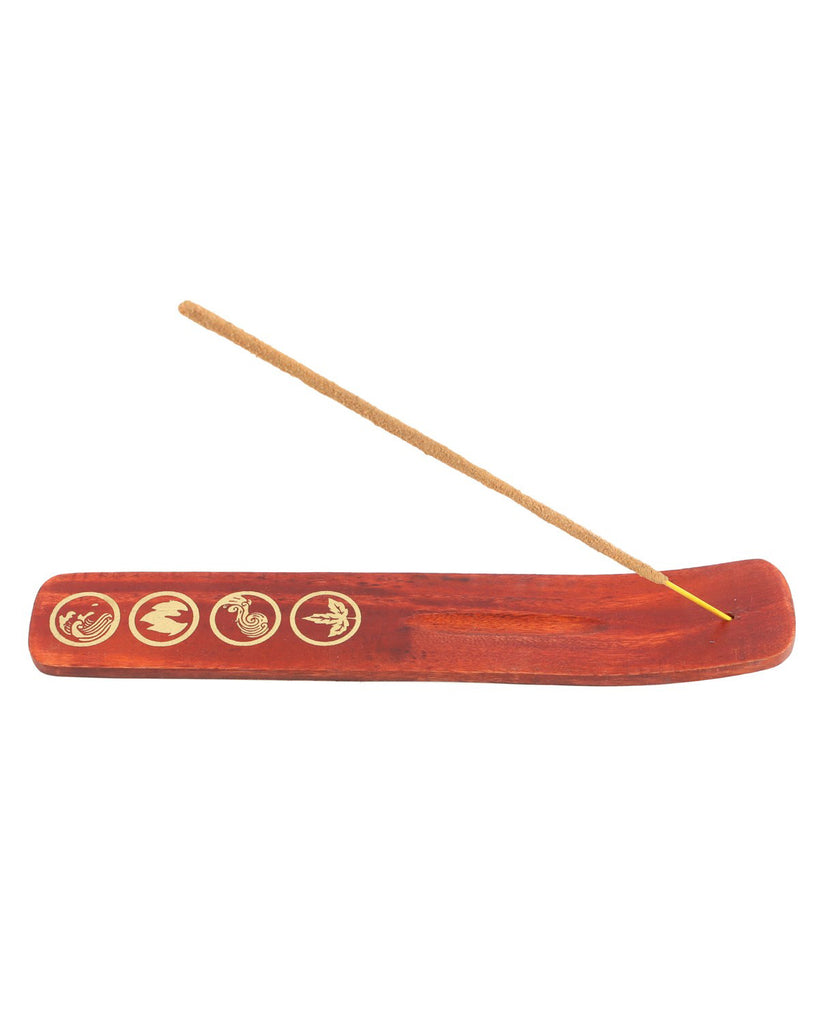 A wooden incense ash catcher with gold elemental symbols engraved and an incense stick burning at one end. Available at Rebel Romance, a small UK brand celebrating alternative style.