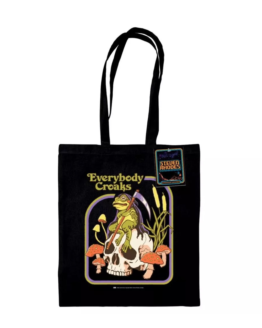 A black tote bag featuring a Steven Rhodes illustration titled “Everybody Croaks.” The design showcases a frog playing a violin while sitting on a skull, surrounded by orange mushrooms and cattails. The text “Everybody Croaks” appears in yellow above the artwork.