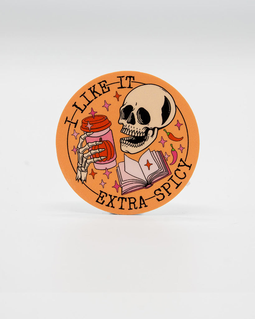 Round die-cut vinyl sticker featuring a grinning skeleton holding a takeaway coffee cup next to an open book, surrounded by sparkles, chillies, and the phrase “I Like It Extra Spicy.” A bold, spooky design perfect for smut readers and lovers of dark humour. Created by Rebel Romance, a small UK brand celebrating alternative style, slow fashion, and cheeky, millennial-friendly bookish gifts.
